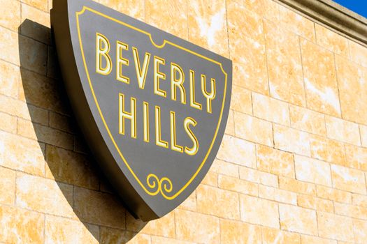 Close-up of the Beverly Hills sign mounted on a sunlit wall, capturing the essence of luxury and glamour.