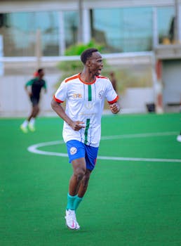 A young soccer player energetically runs on a green field during a sunny day match.