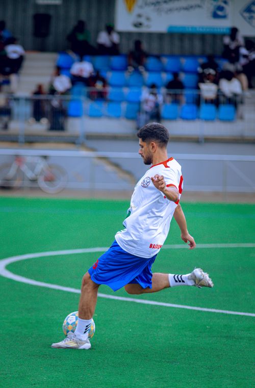 Free Dynamic action shot of a soccer player kicking a ball on a green outdoor field. Stock Photo