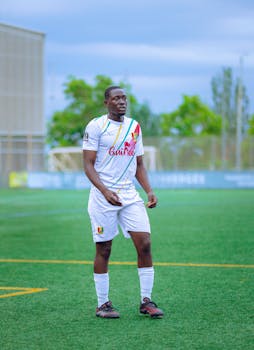 Young male soccer player in uniform on an outdoor field under bright daylight.