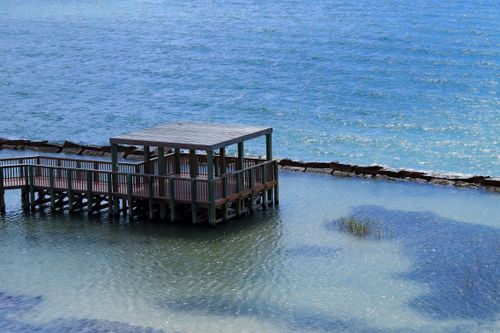 Free Serene view of a wooden gazebo on a calm oceanfront with blue water. Stock Photo