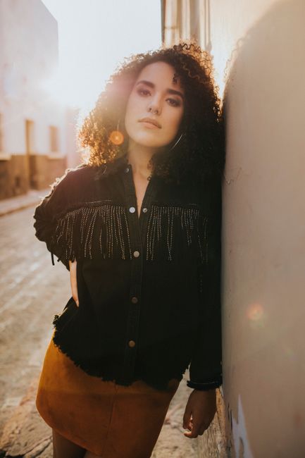 Stylish woman with curly hair poses in the golden sunlight of Santiago de Querétaro.