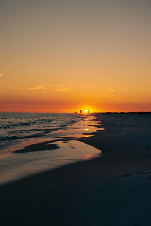 Free Silhouette of sunset reflecting on calm waters of Destin Beach, Florida, capturing serene beauty of coastal landscape. Stock Photo