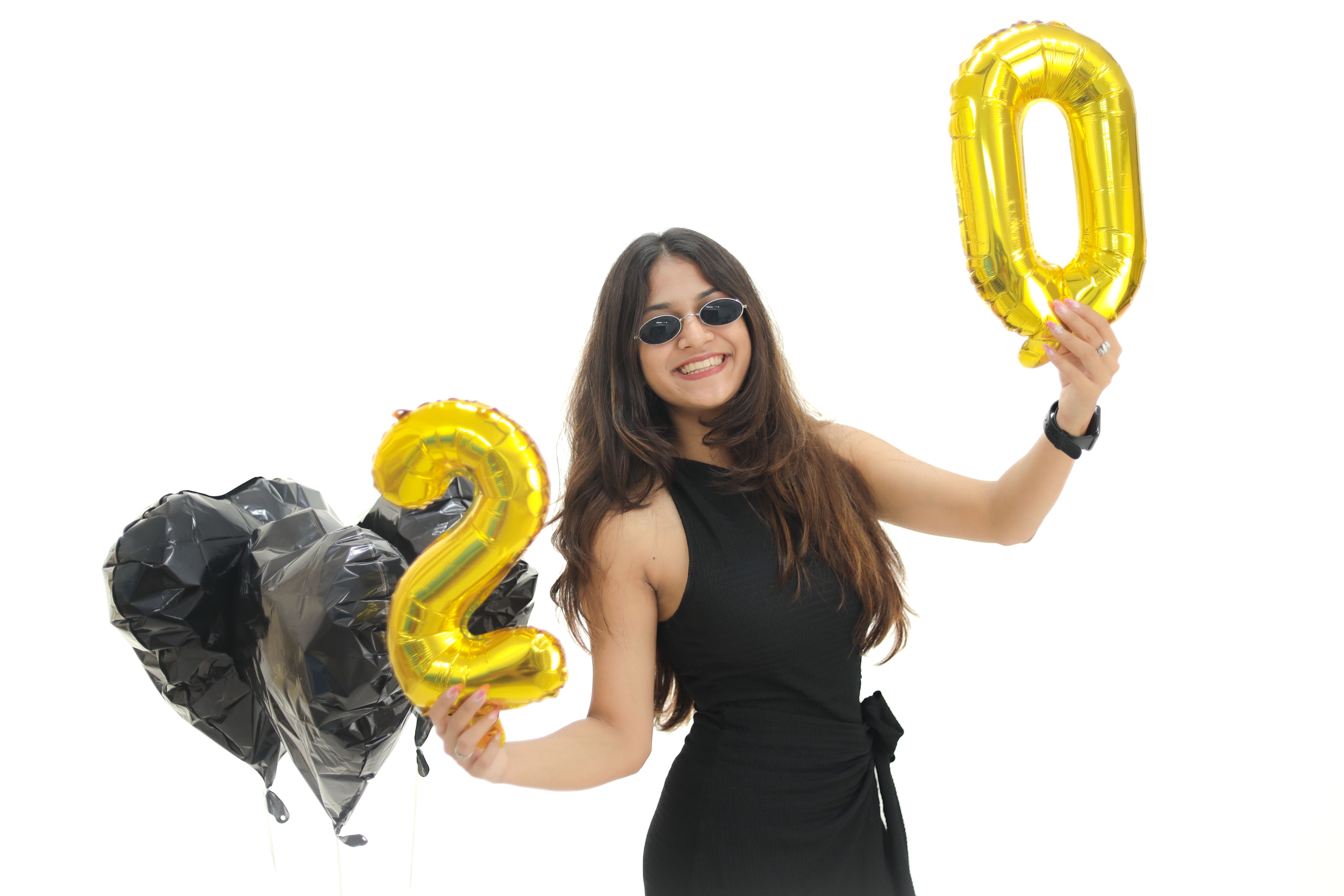 Smiling woman holding golden balloons for 2020, celebrating New Year with black heart balloons.