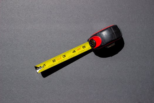 Close-up of a yellow measuring tape on a dark surface under bright lighting.