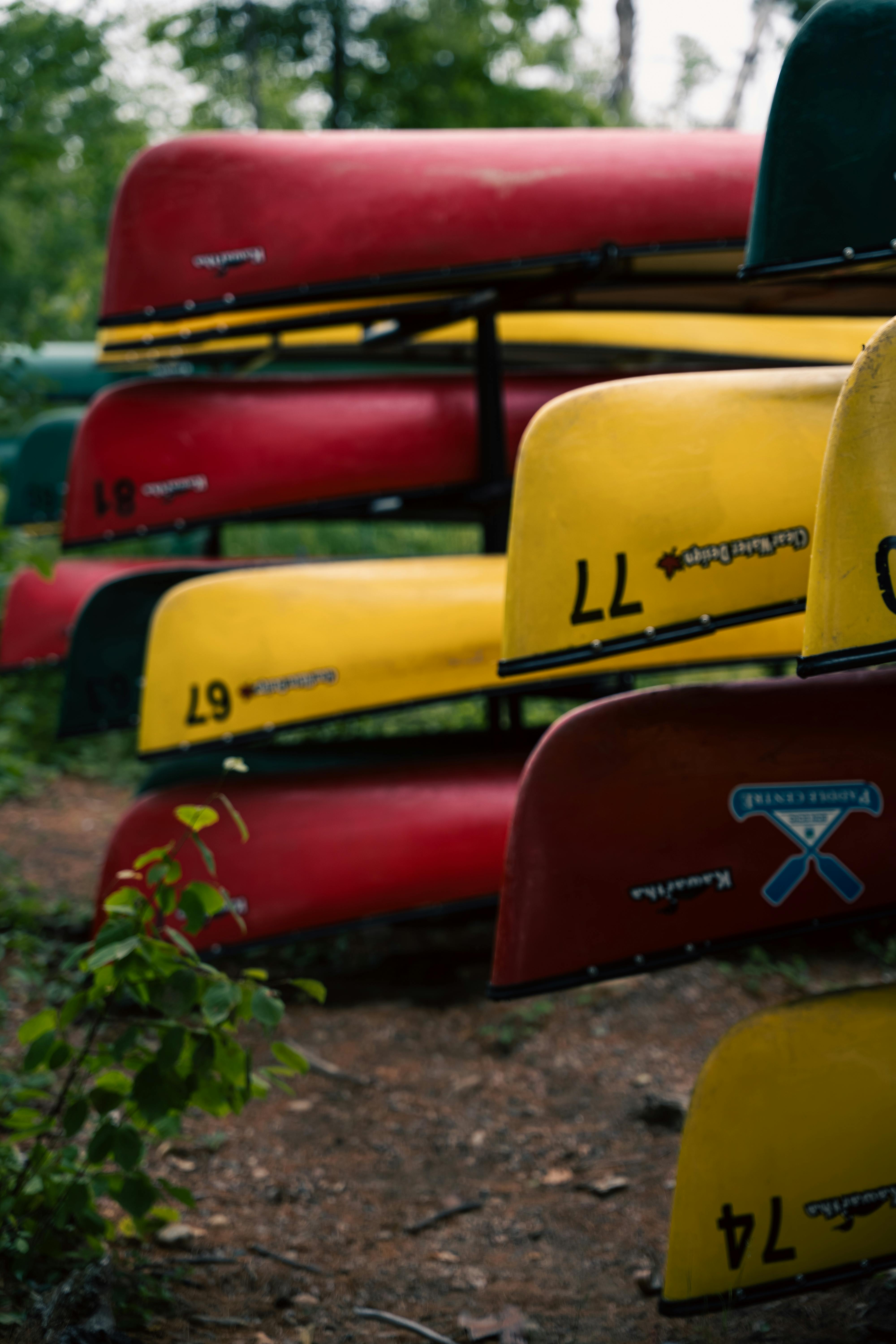 Vibrant red and yellow canoes stacked in an outdoor natural environment.