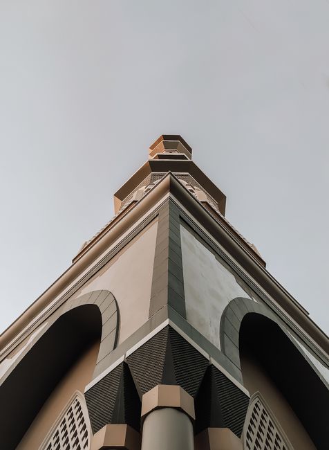 Low angle architectural view showcasing the geometric spire of a modern building against a clear sky.
