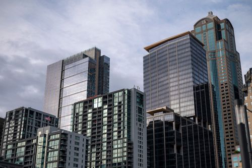 Free A cluster of modern skyscrapers with reflective glass facades set against a cloudy sky. Stock Photo
