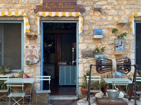 Cozy entrance of a traditional stone cafe with rustic decor in a Greek village.