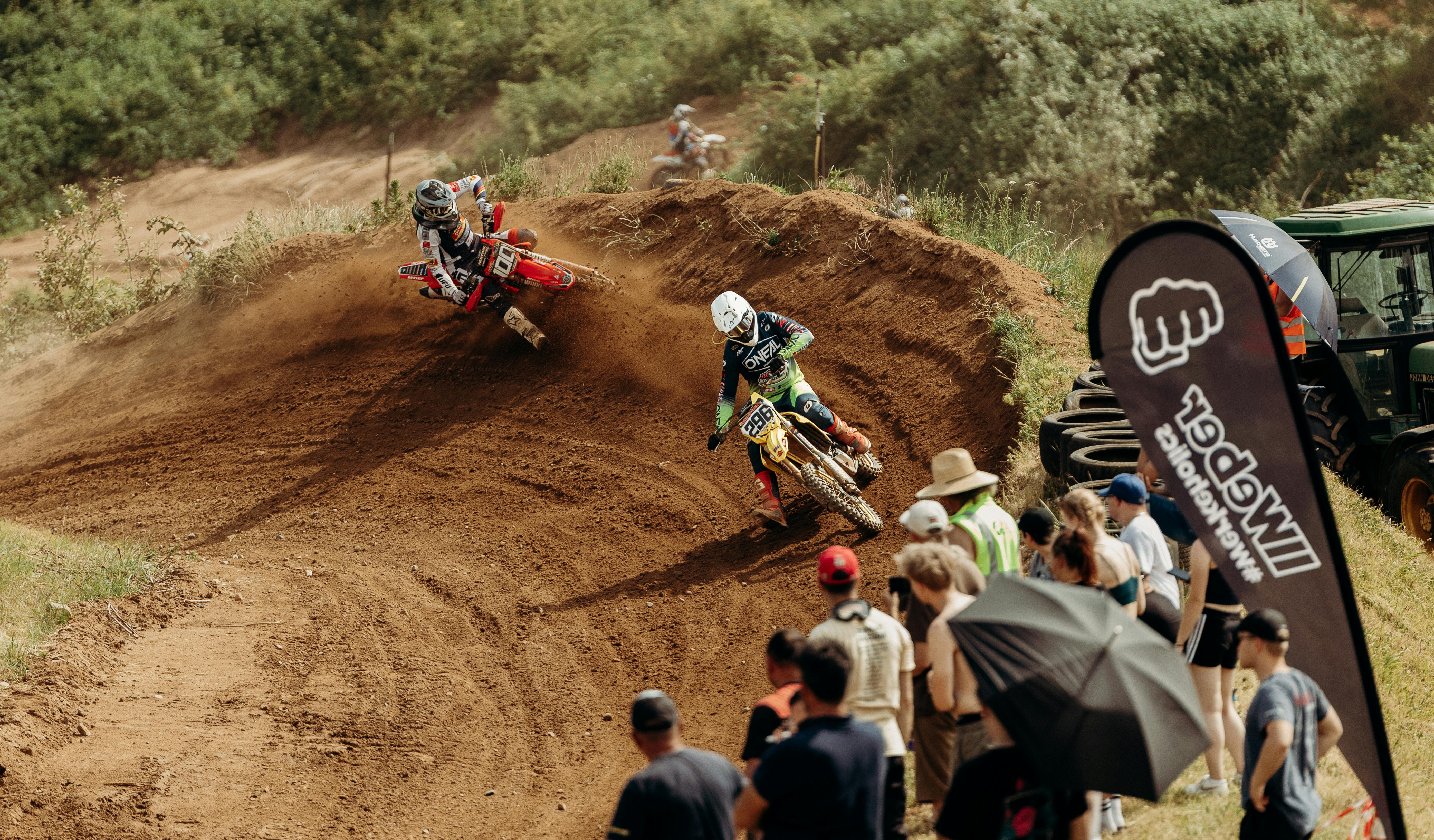 High-speed motocross action on a dirt track in Schaafheim with an enthusiastic crowd watching.