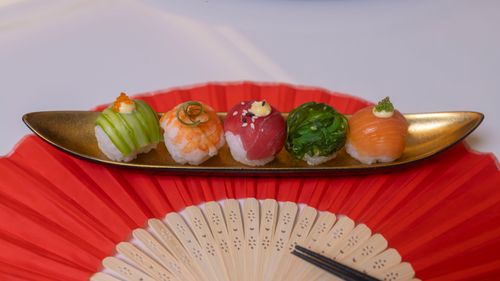 Free An artistic display of five assorted sushi pieces on a decorative plate, presented with a fan. Stock Photo