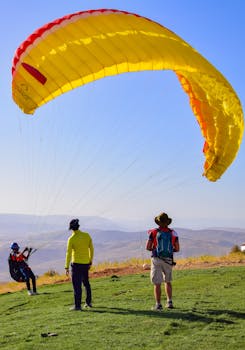 Thrilling paragliding experience captured in Siirt, Türkiye, featuring vibrant yellow parachute against stunning landscape.