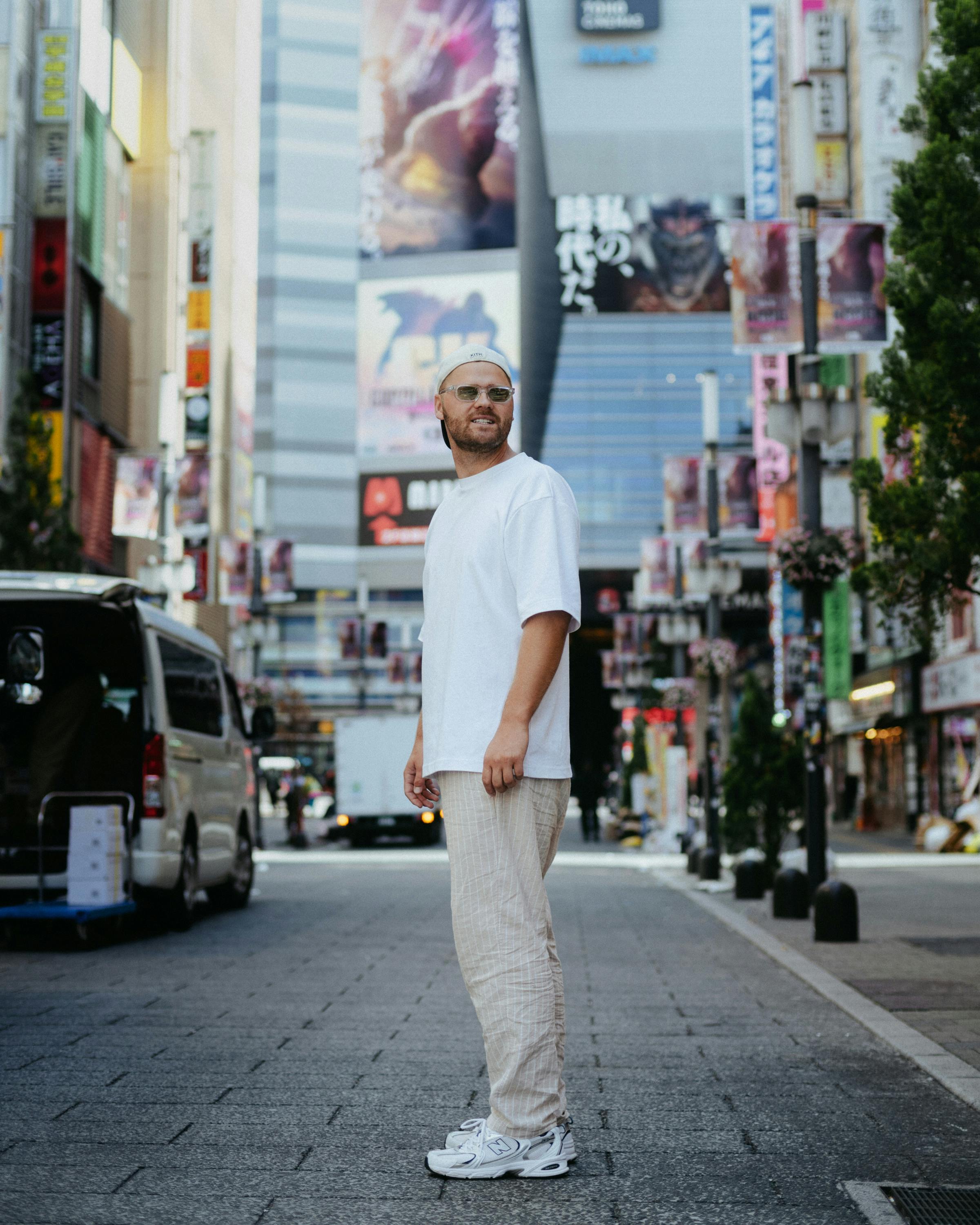 A man walks through a vibrant street in Shinjuku, Tokyo, surrounded by colorful billboards and modern architecture.