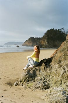 A woman in casual attire enjoys the serene Arch Cape beach. Oregon coast scenery.