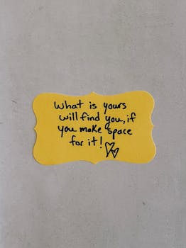 Yellow paper card with an inspirational handwritten quote on a light background.
