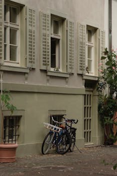 Charming vintage European street scene with bicycles against a wall under shuttered windows.