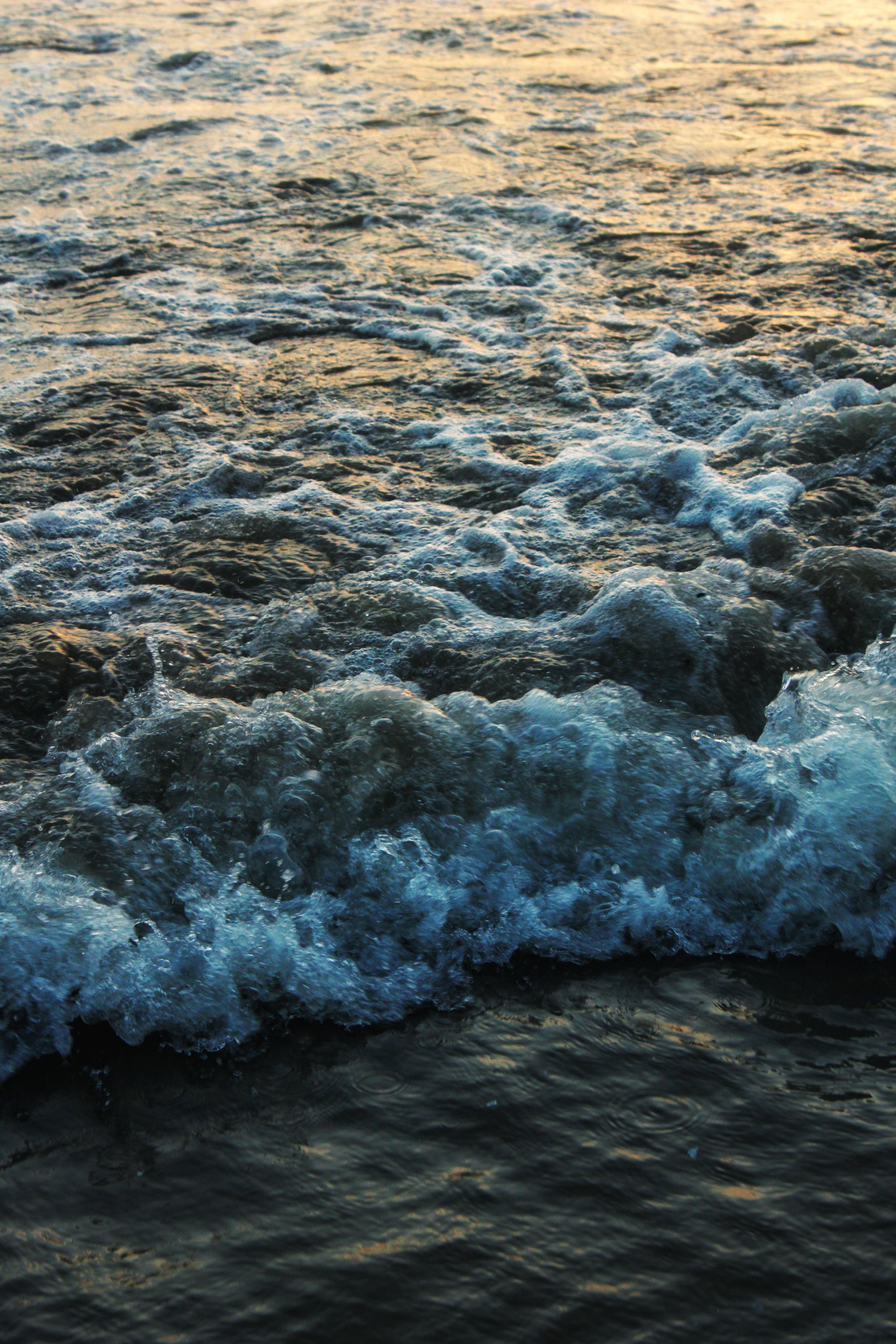 Calm evening waves with golden sunset lighting near Mumbai, India.