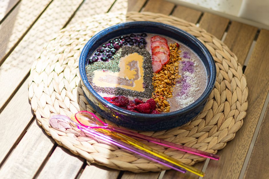 Vibrant smoothie bowl with berries, chia seeds, and granola on woven placemat.