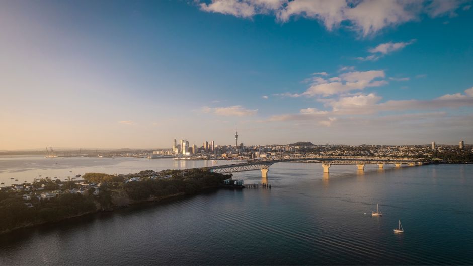 Stunning aerial view of Auckland city skyline and Harbor Bridge at sunset.