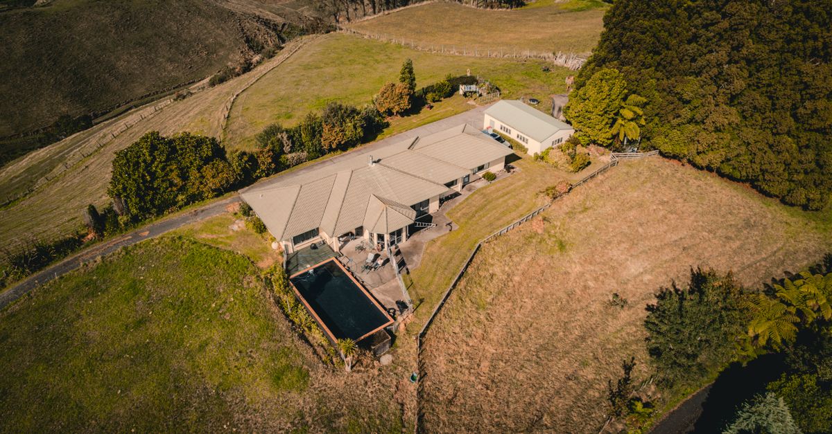 Stunning aerial view of a rural homestead with a pool, surrounded by lush landscapes in Tauranga, New Zealand.