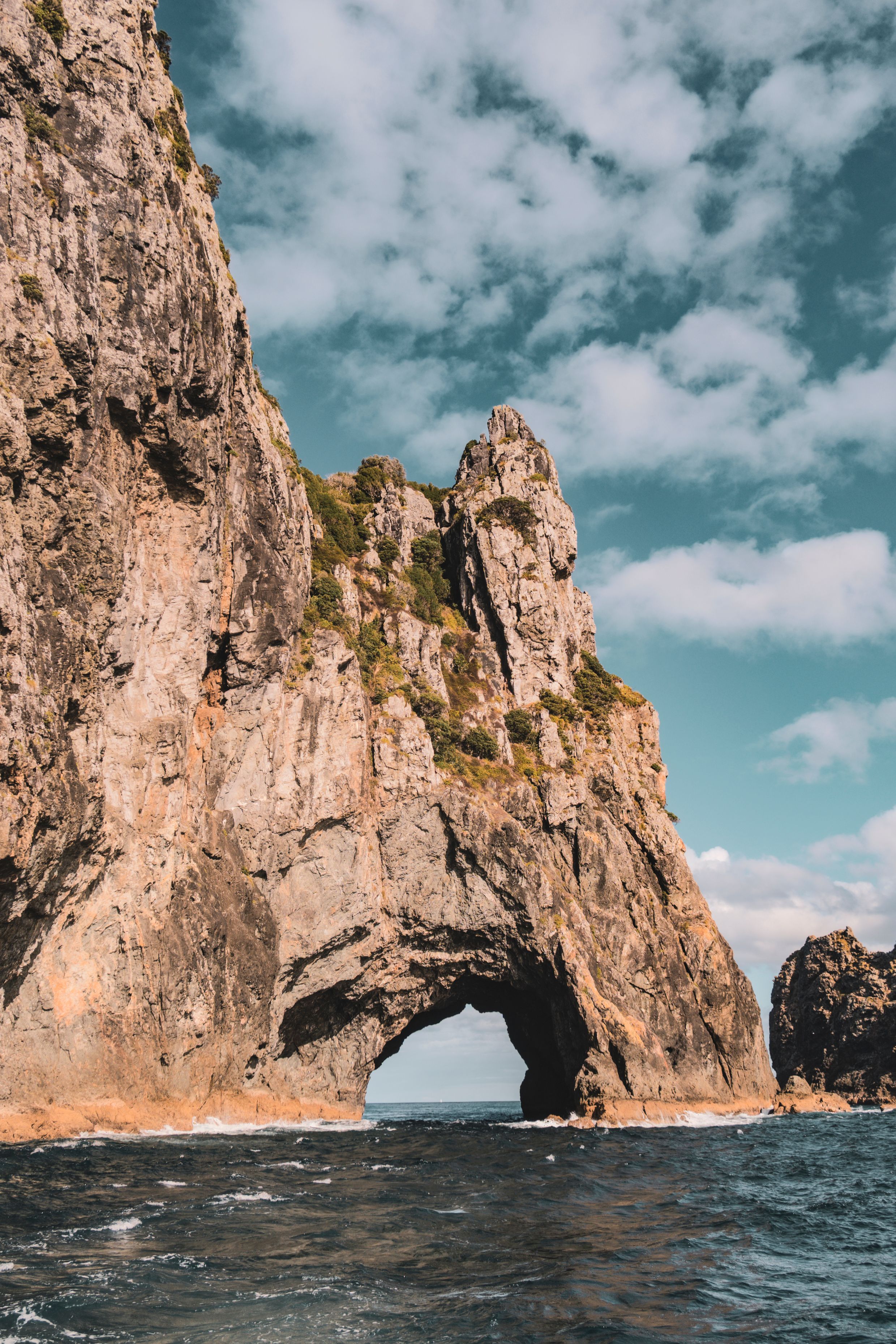 Dramatic view of the Hole in the Rock formation in Northland, New Zealand, surrounded by sea.