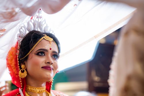 Free Close-up of a traditional Indian bride wearing gold jewelry and a red veil, looking joyful. Stock Photo