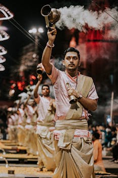 Priests performing the Ganga Aarti at night in Varanasi, India, with traditional attire and incense.