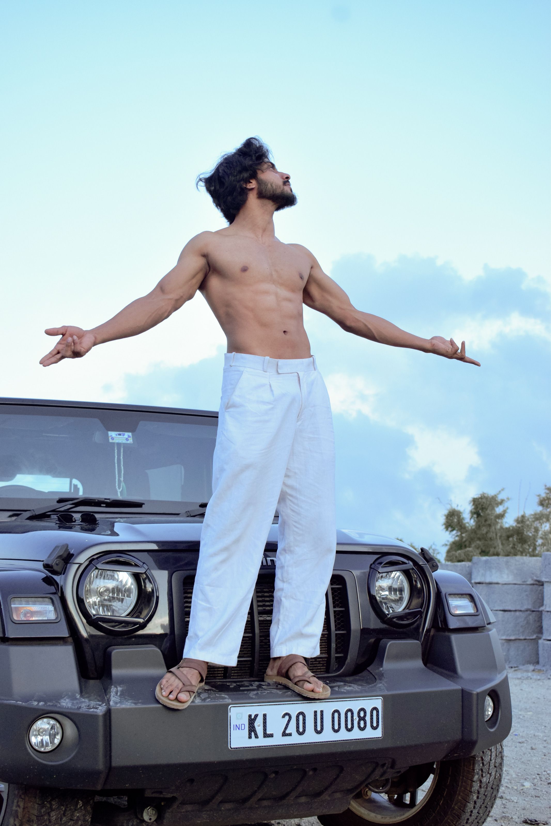Man standing on SUV in outdoor setting, showcasing confidence and freedom.