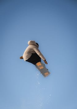 A snowboarder performs a jump against a clear sky at Le Grand-Bornand ski resort in France.