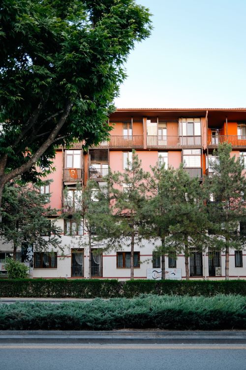 Free Contemporary apartment building with lush greenery and clear blue sky. Stock Photo