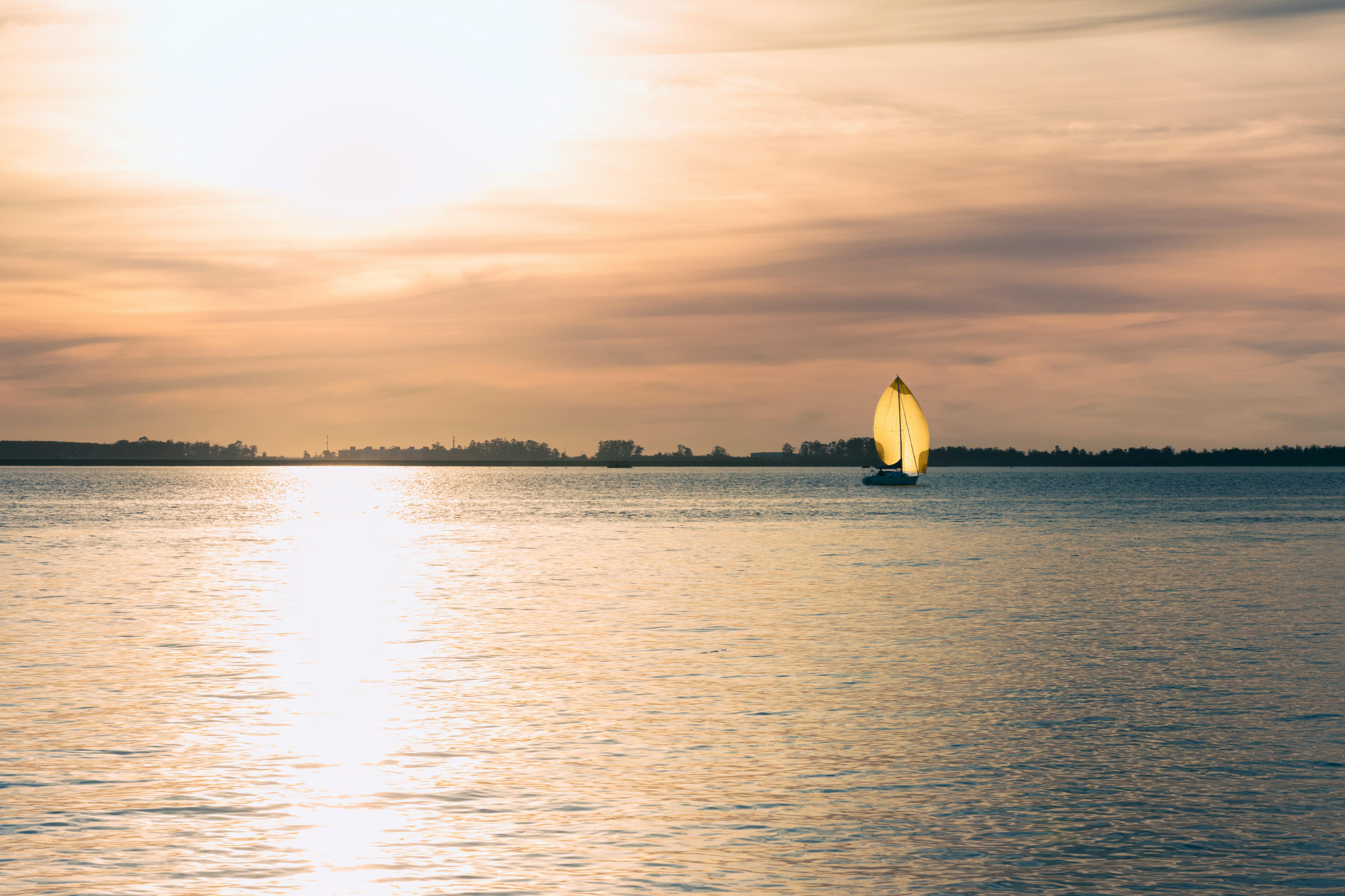 Peaceful sunset scene with a sailboat on Guaíba River in Porto Alegre, Brazil.