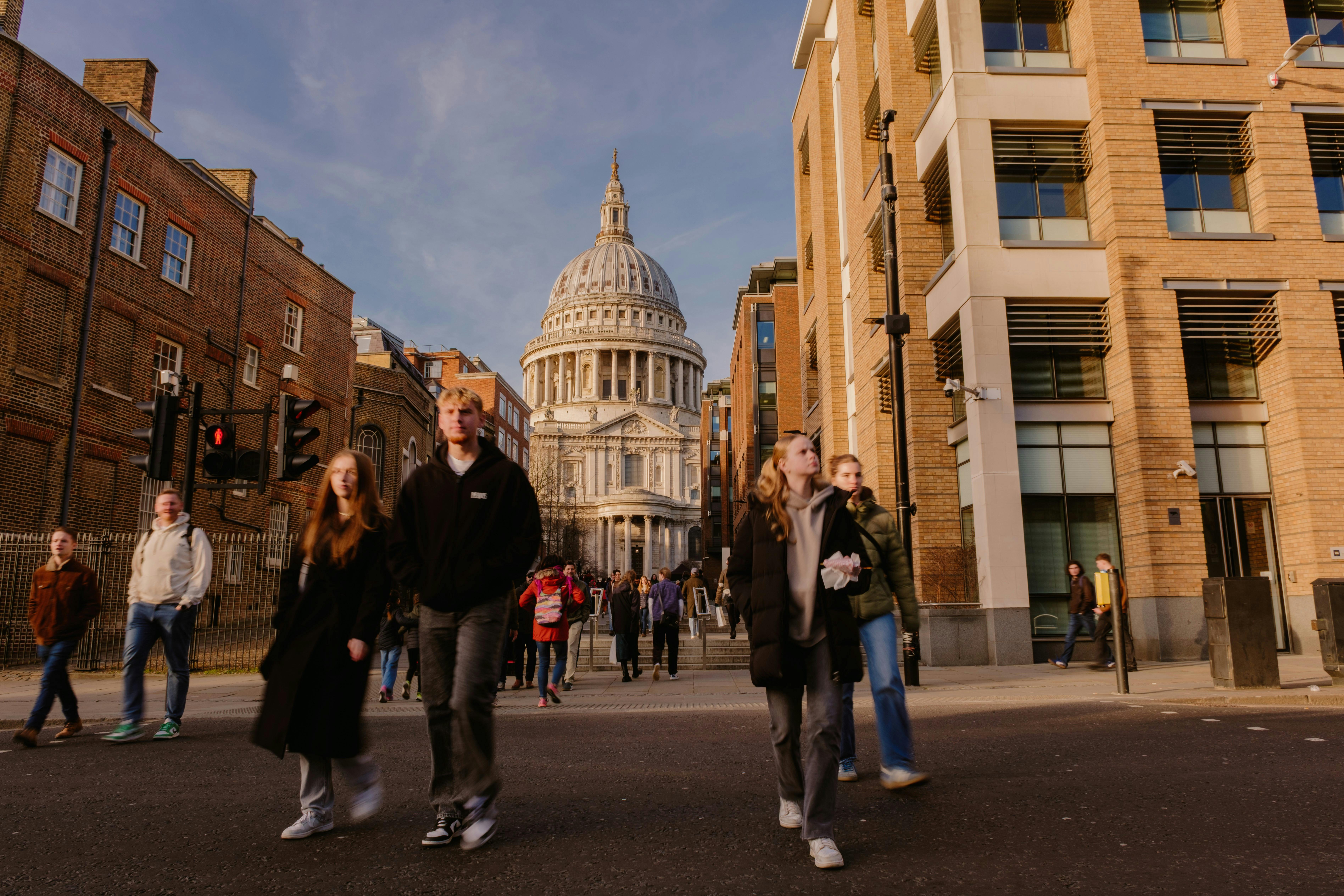 People walking in front of St. Paul's Cathedral in London on a sunny day.