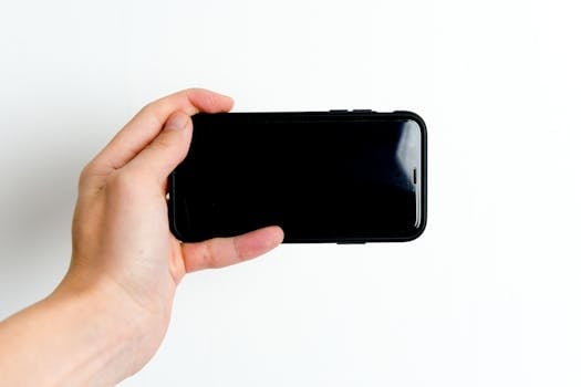 Hand holding a smartphone with a blank screen, perfect for technology and communication themes.