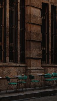 Charming empty street cafe set against a historic stone facade.