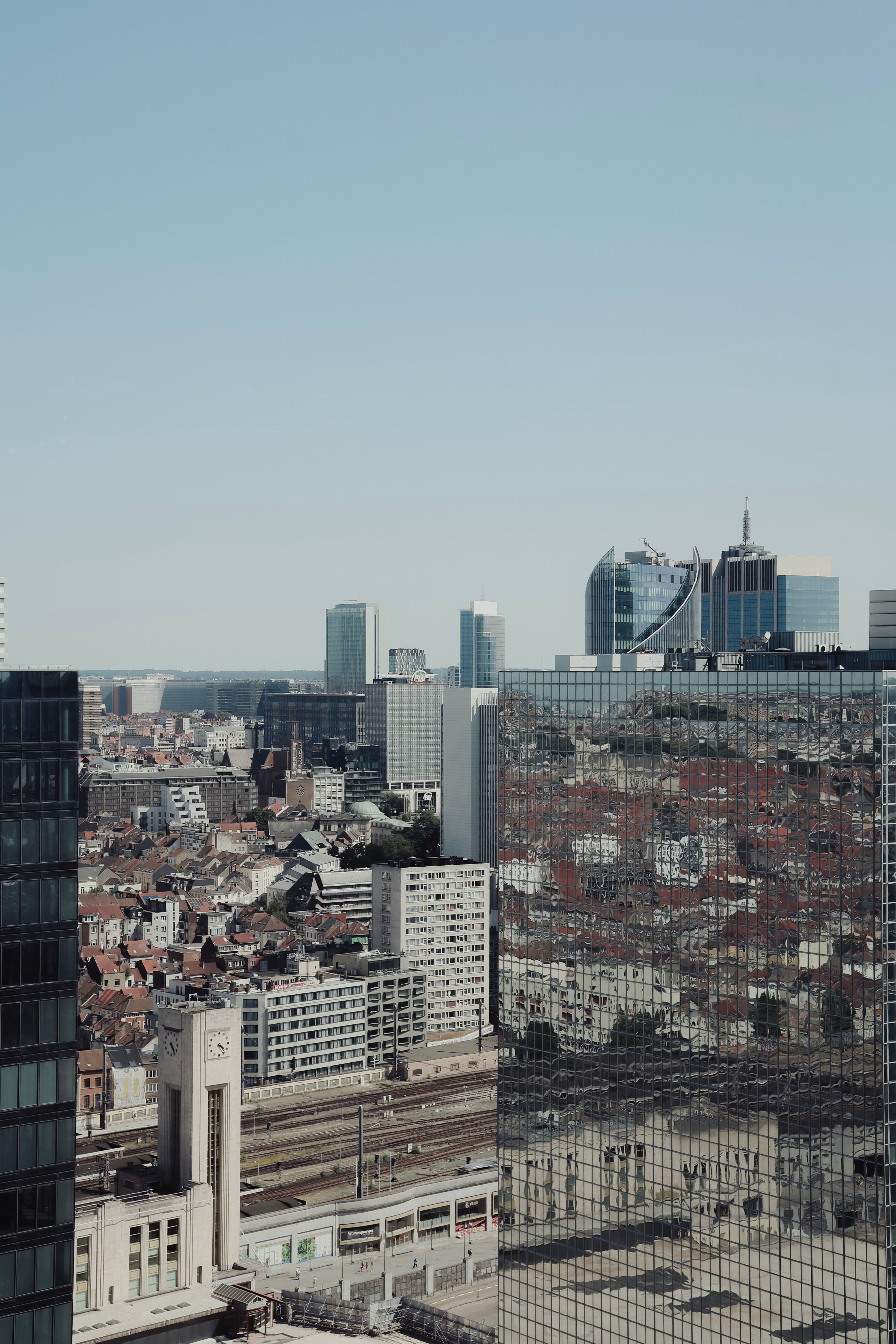 Aerial view of Brussels cityscape featuring modern architecture and reflective skyscrapers under a clear blue sky.