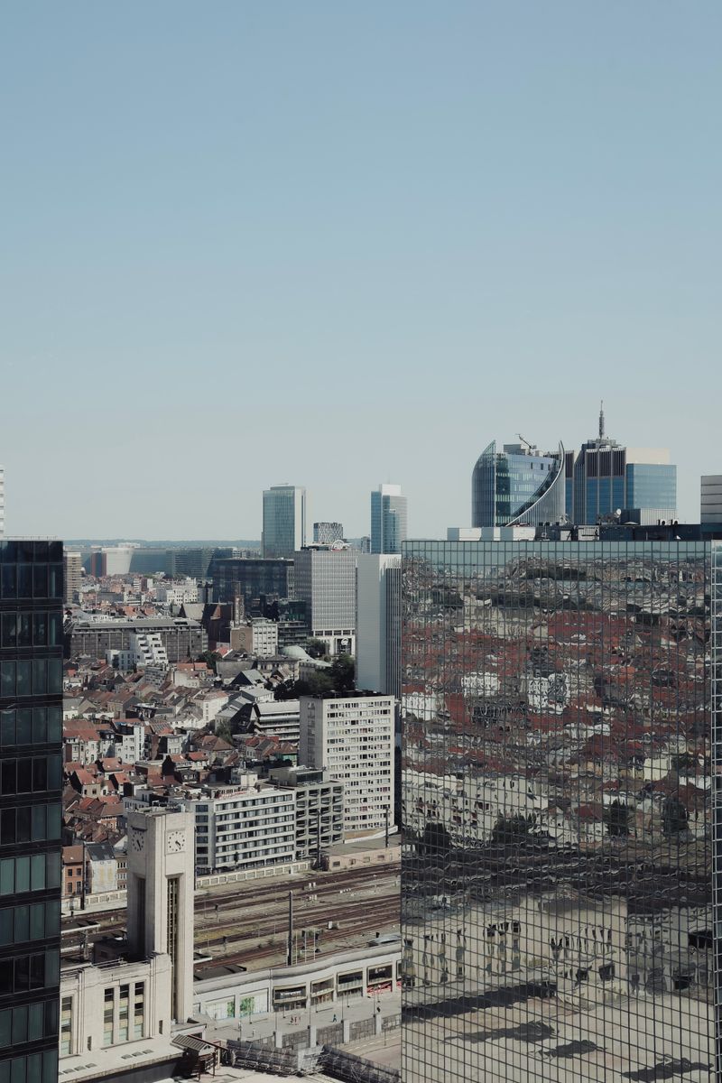 Aerial view of Brussels cityscape featuring modern architecture and reflective skyscrapers under a clear blue sky.