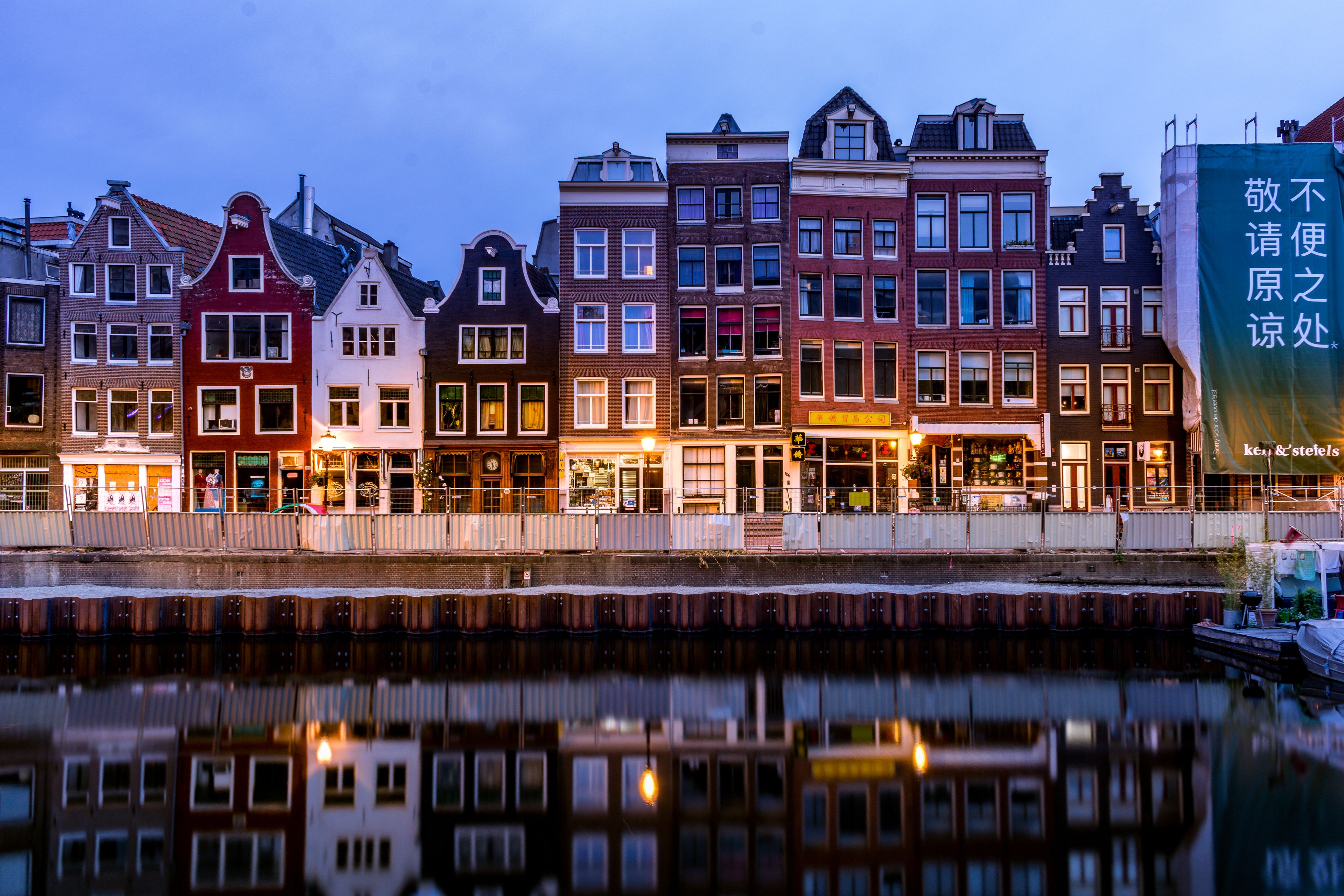 A picturesque view of colorful canal houses reflecting on the water in Amsterdam, Netherlands.