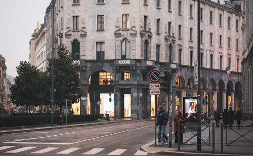 Free Street view showcasing historic architecture in Milan, Italy with pedestrians and traffic lights. Stock Photo