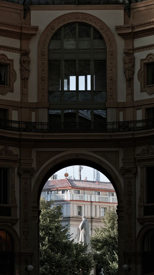 Free A stunning architectural photograph showcasing a view through an arched gallery highlighting classic European design. Stock Photo