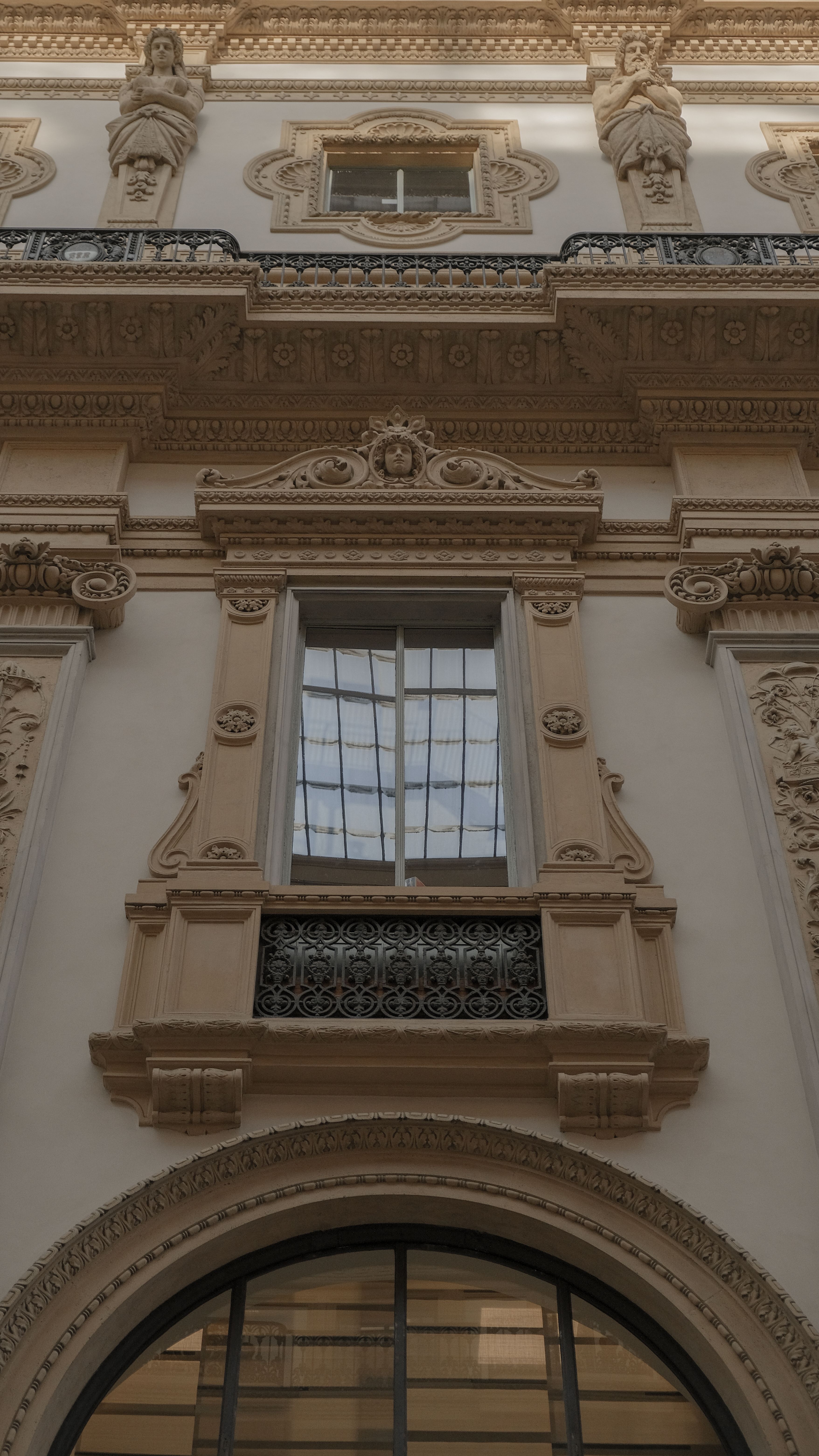 Detailed view of an ornate Neo-Renaissance building facade with windows and classical sculptures.