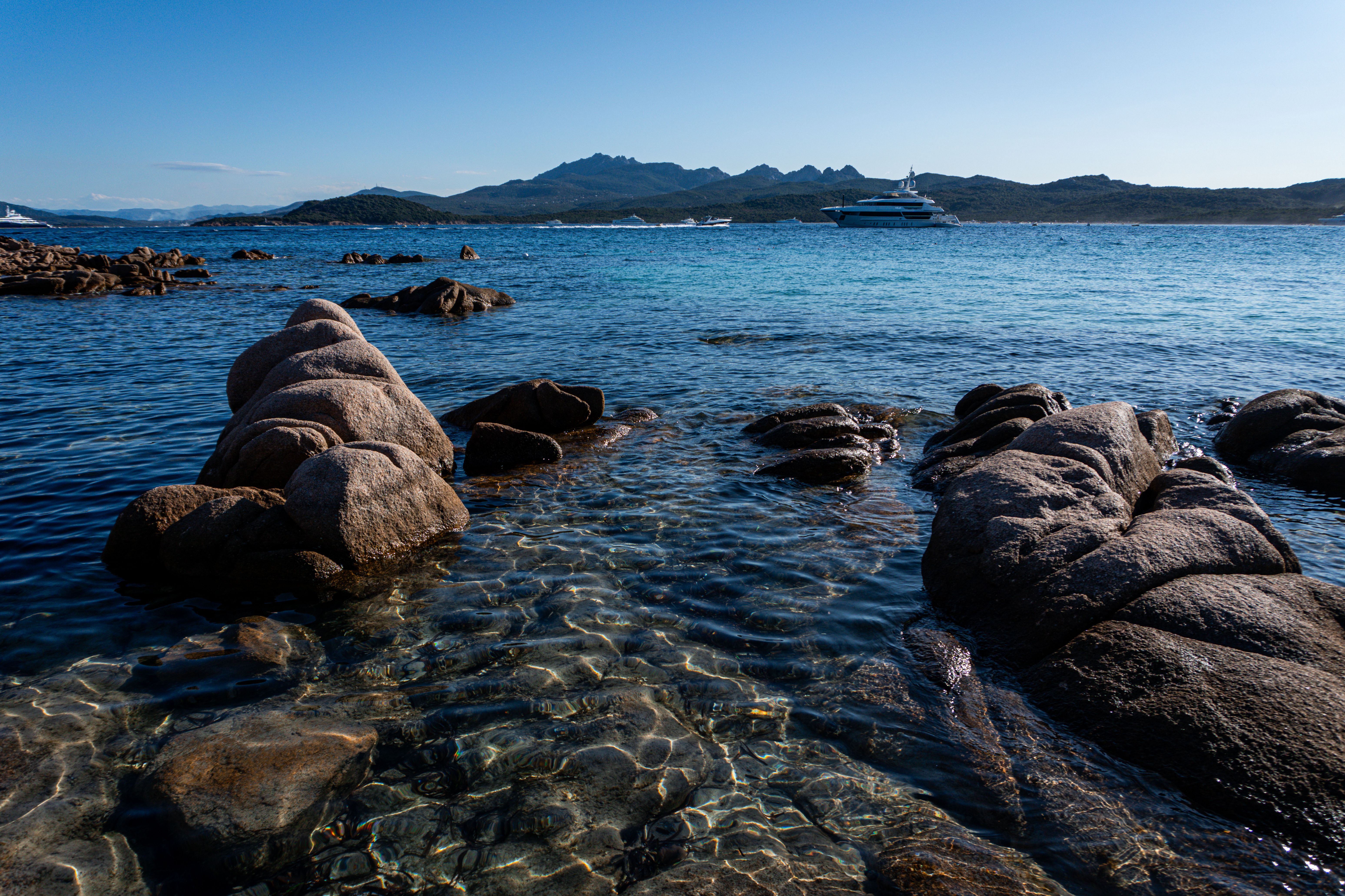 Scenic Sardinian Coastal View with Yacht and Rocks