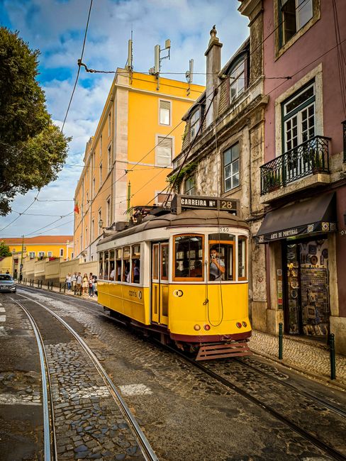 Photo of a classic yellow tram navigating the charming streets of Lisbon, Portugal.