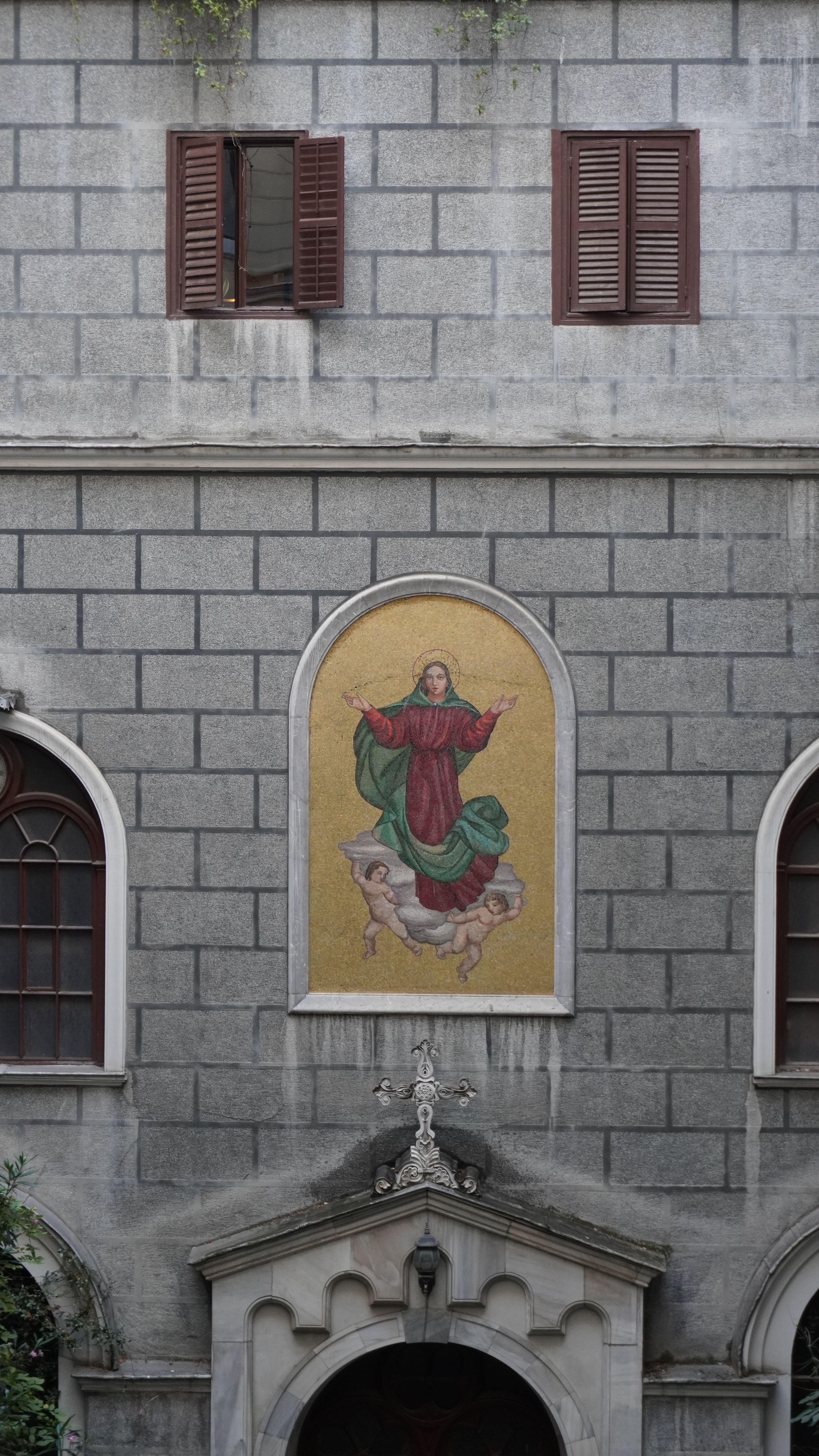 Stone facade of a historic building featuring religious artwork and arched windows.