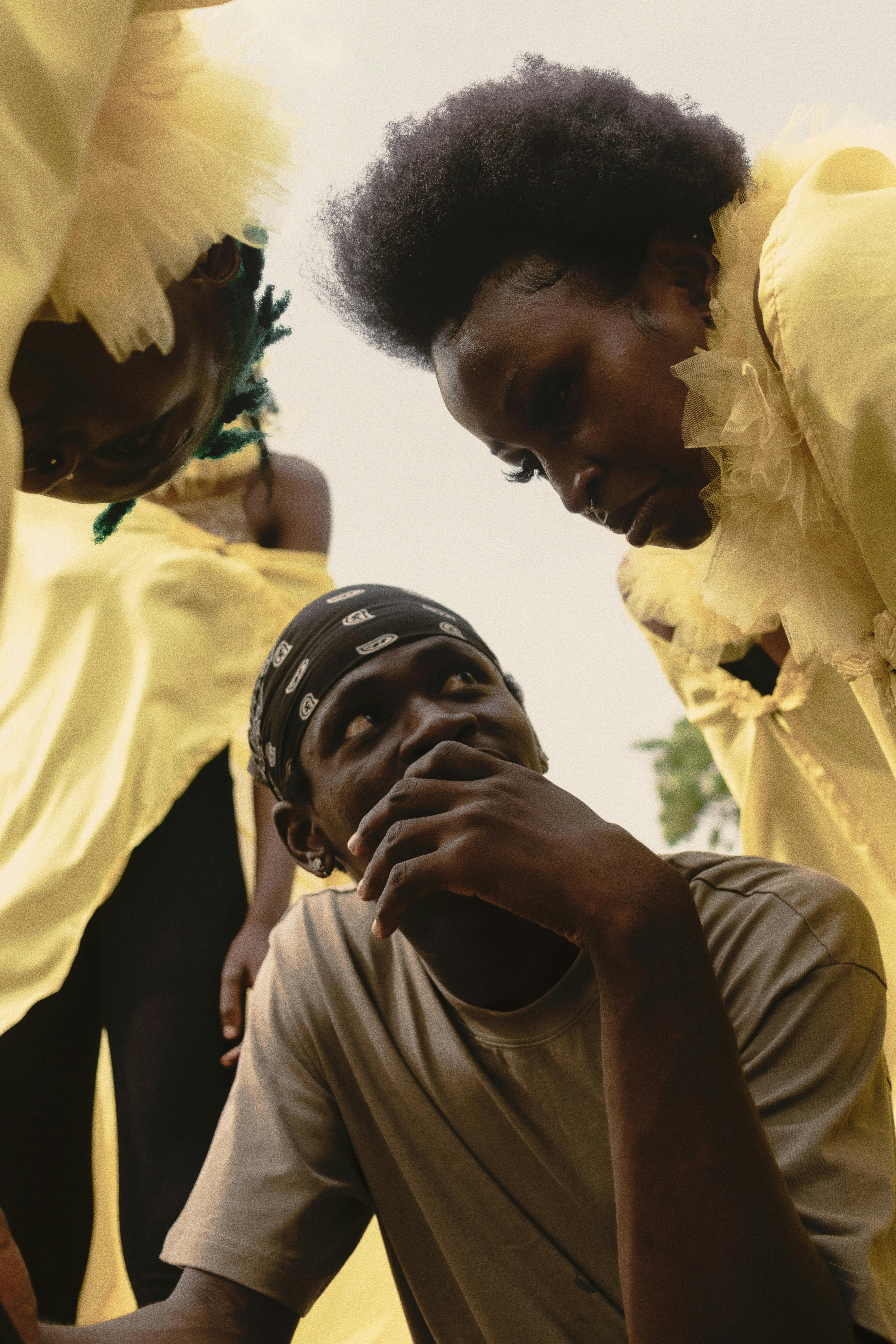 бесплатная Группа людей в выразительных позах, одетых в желтые костюмы, на открытом воздухе в Нигерии. Стоковое фото