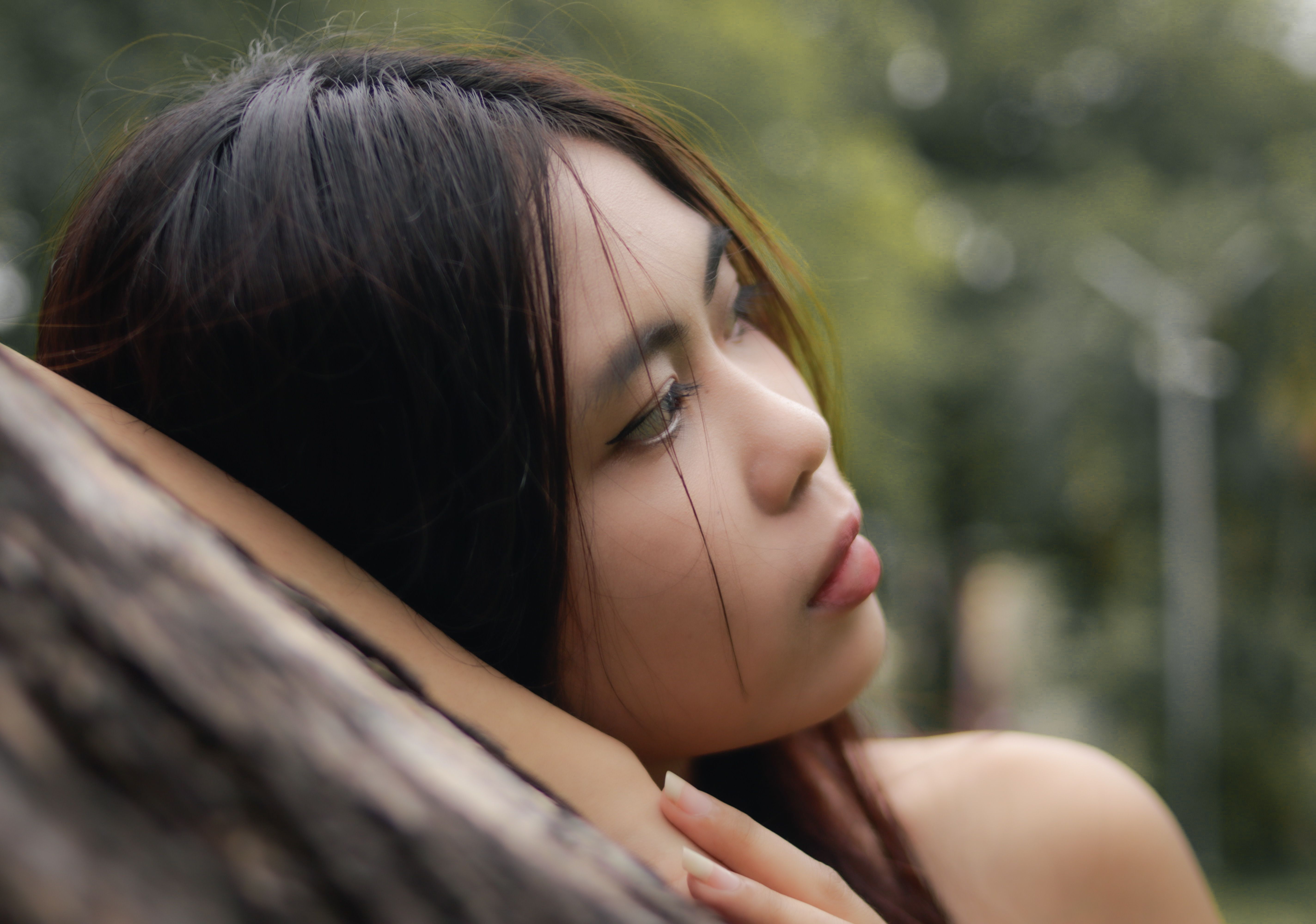 Pensive Woman Resting Against Tree Outdoors