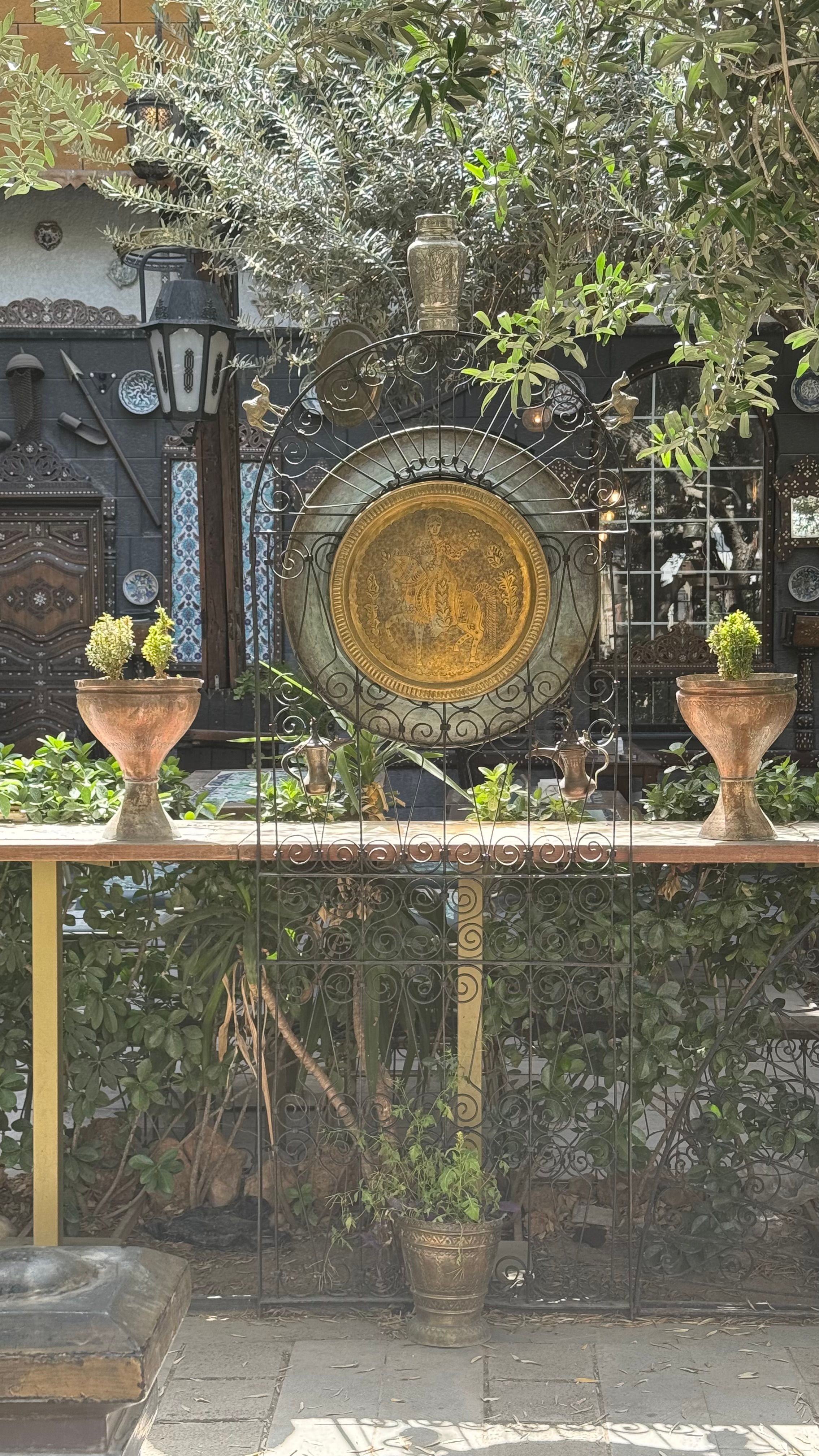 Intricate metalwork and potted plants in a Damascus courtyard, showcasing traditional Syrian decor.