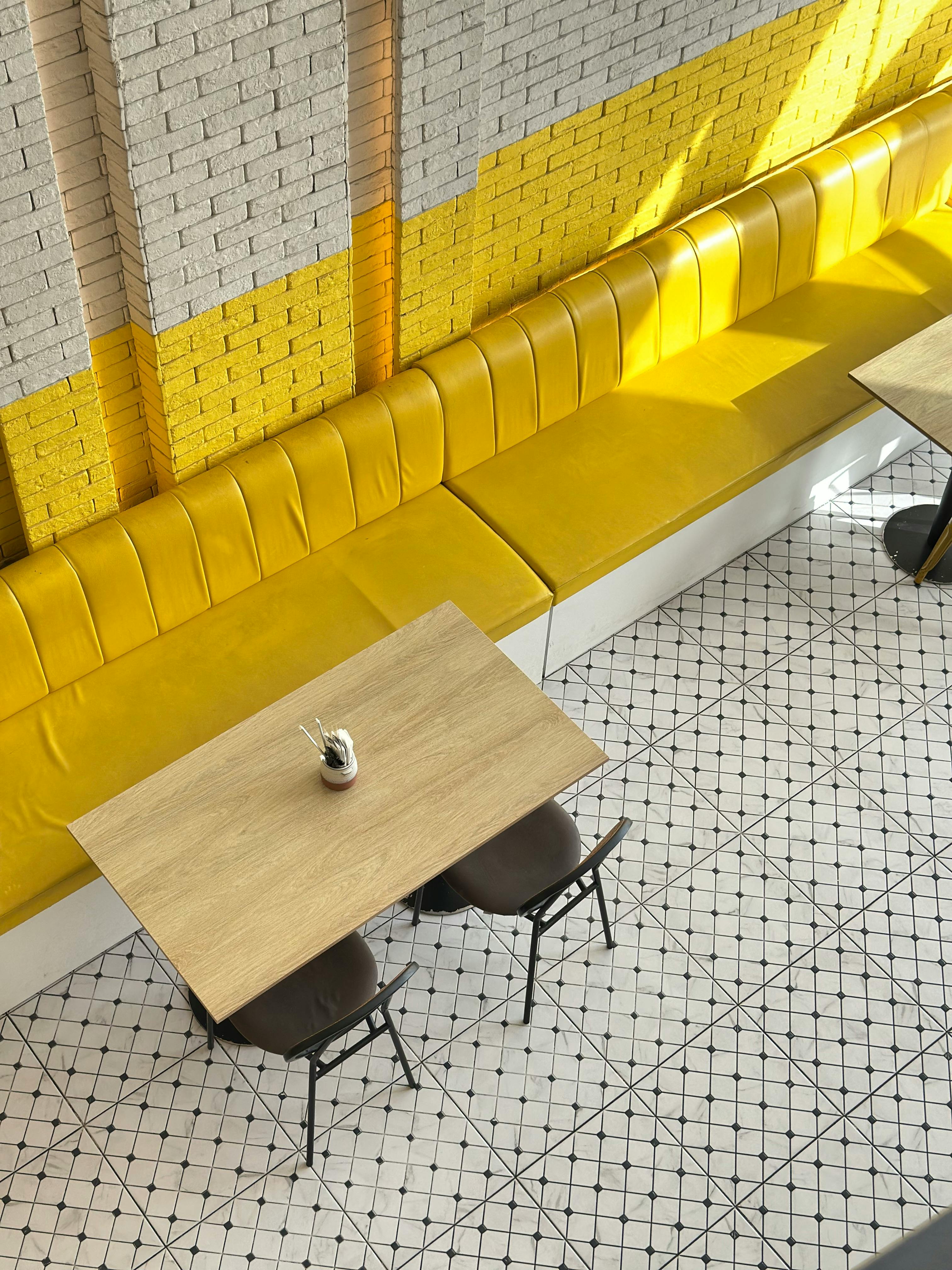 Free Aerial view of a trendy cafe with yellow seating and geometric flooring. Stock Photo