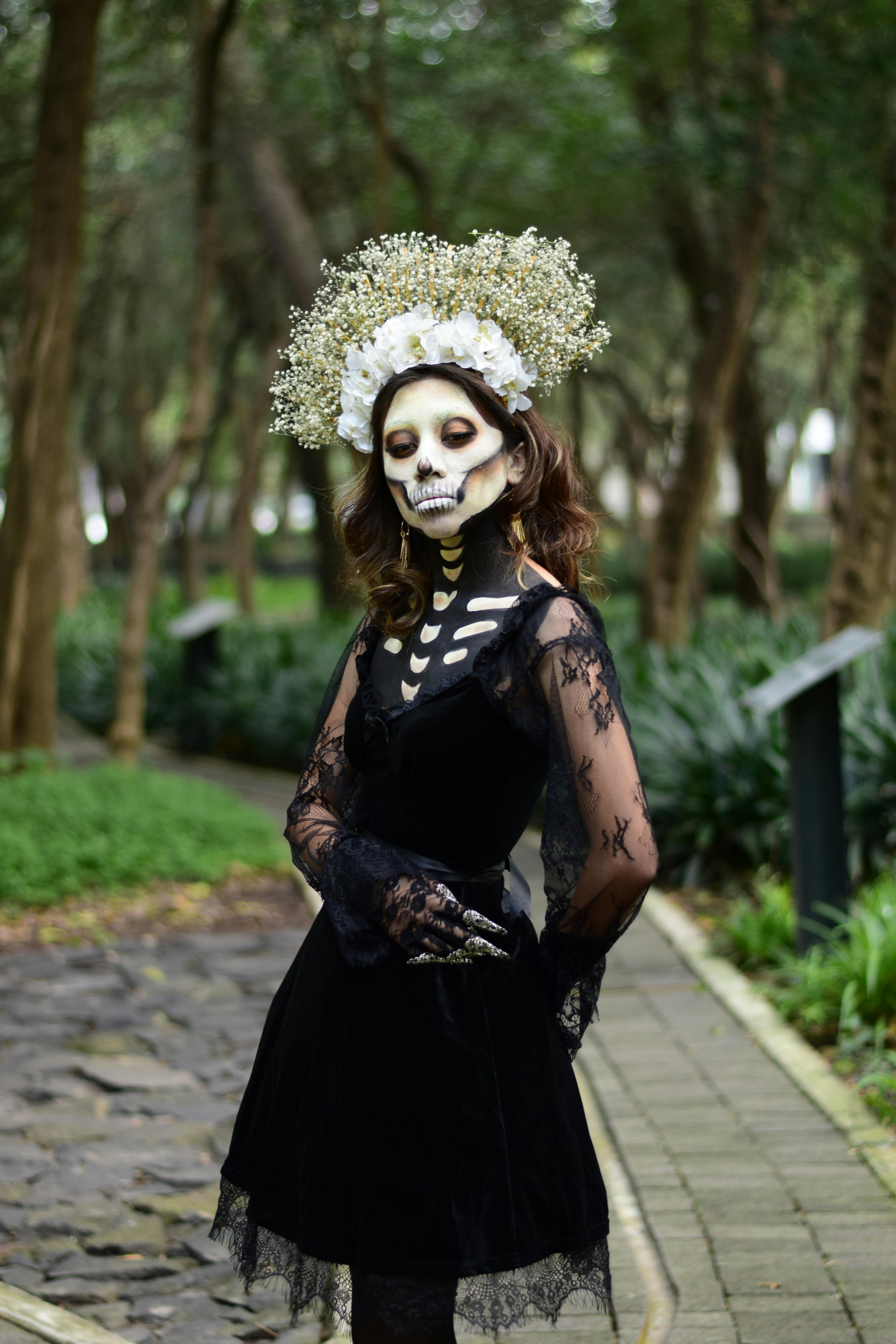 Dramatic gothic portrait of a woman with skeleton makeup in a lush forest.