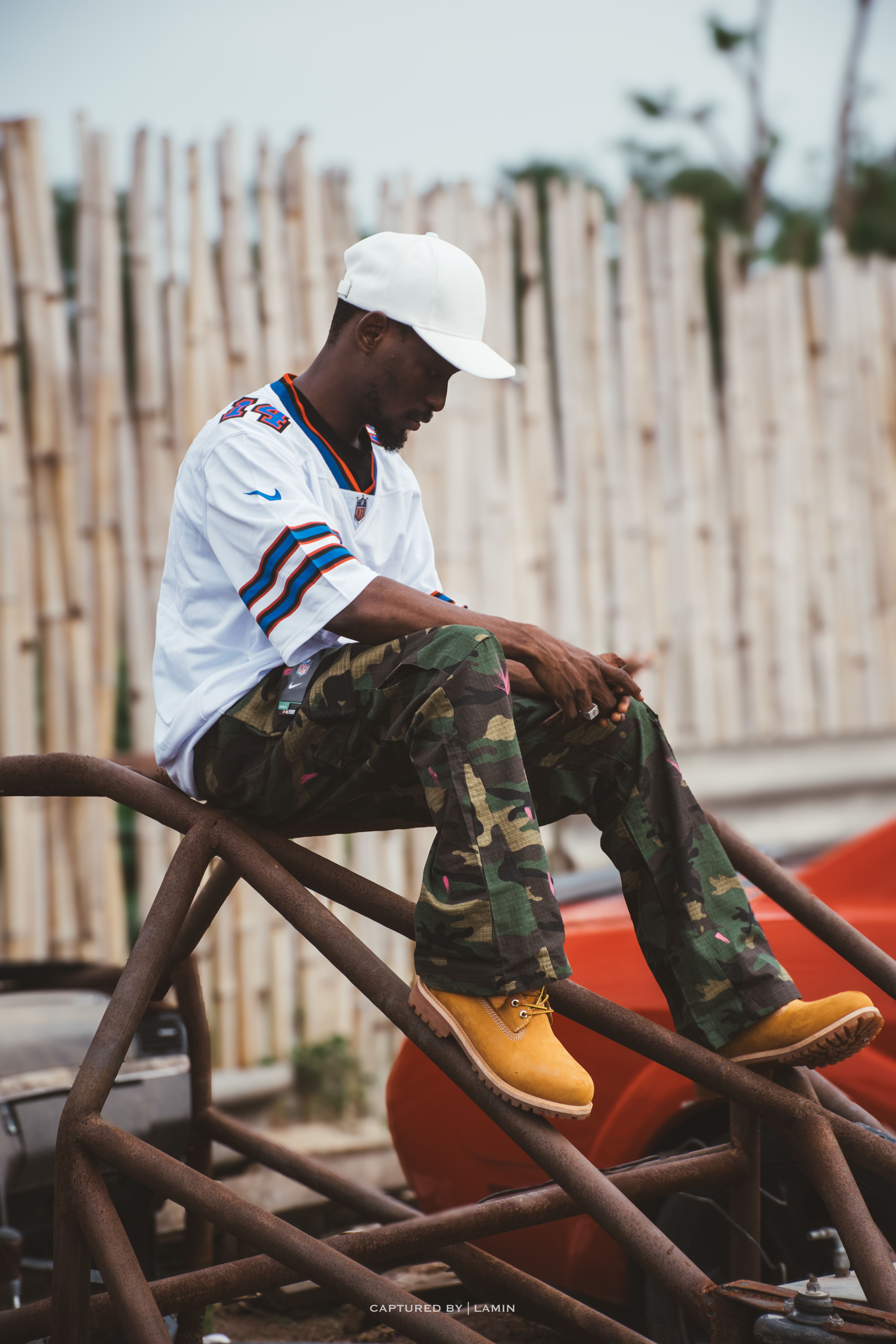 African male model in outdoor fashion setup wearing camouflage pants and Timberland boots.