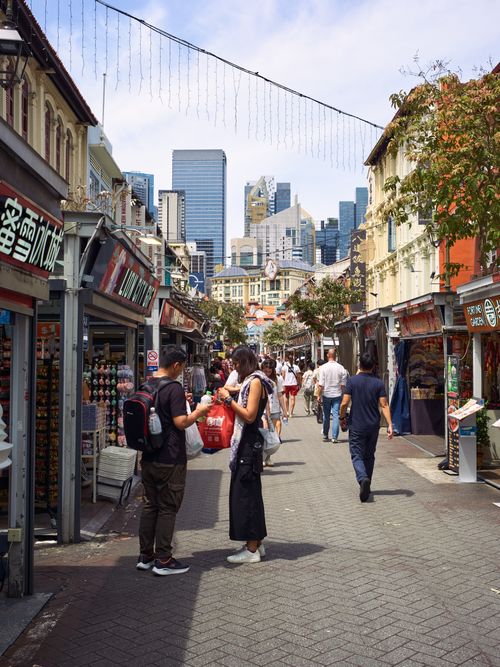 Free Vibrant street life in Singapore's Chinatown with shops and skyscrapers. Stock Photo